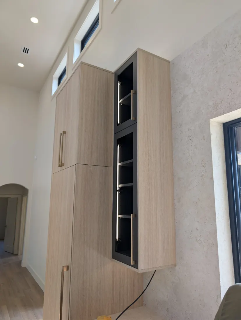 A tall wood-grain cabinet with a black display section lit from inside by LED strips