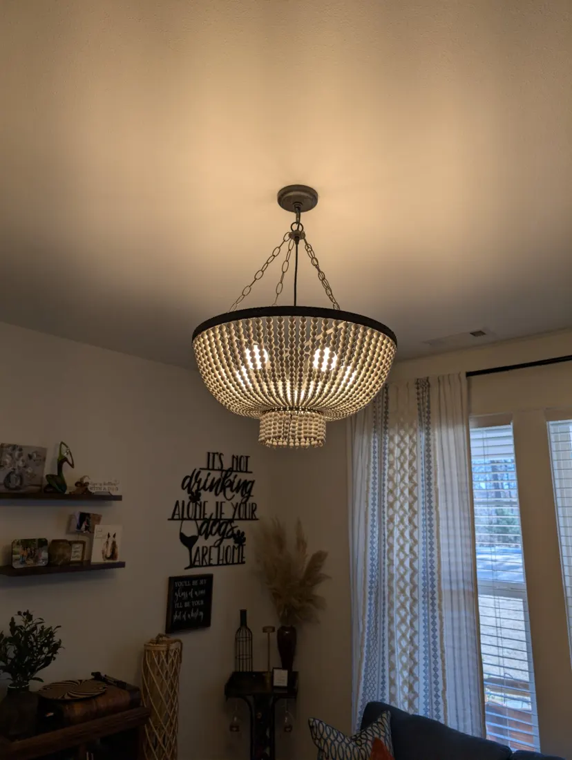 A beaded drum chandelier with a black frame hanging in a living room