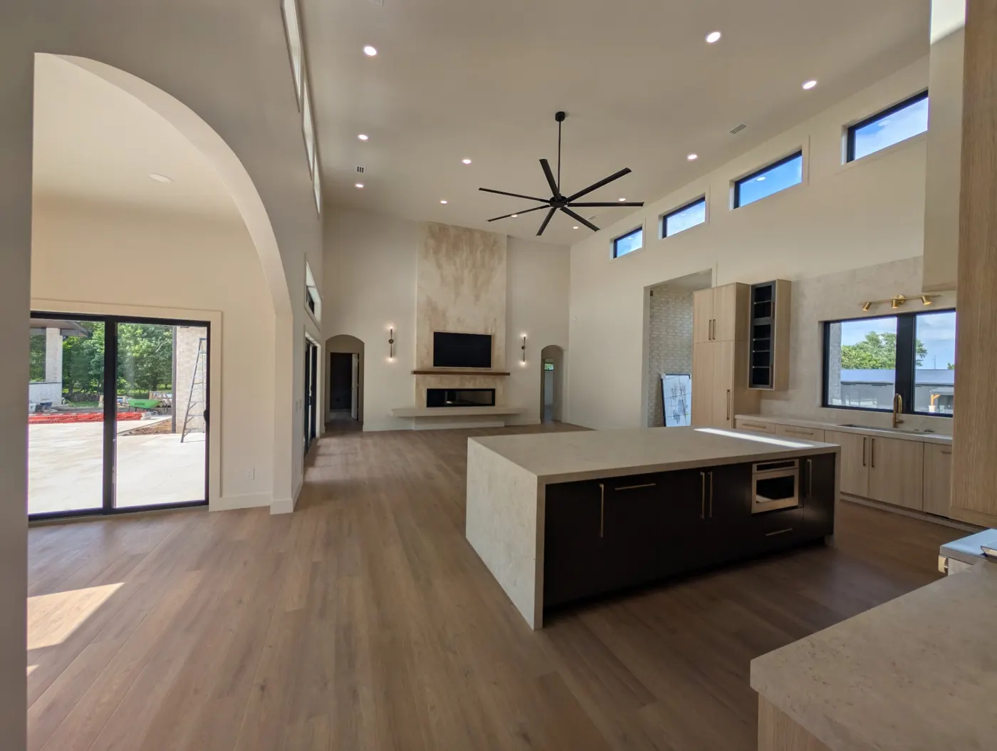 An open kitchen and living room with recessed lights over a large island and a fireplace wall