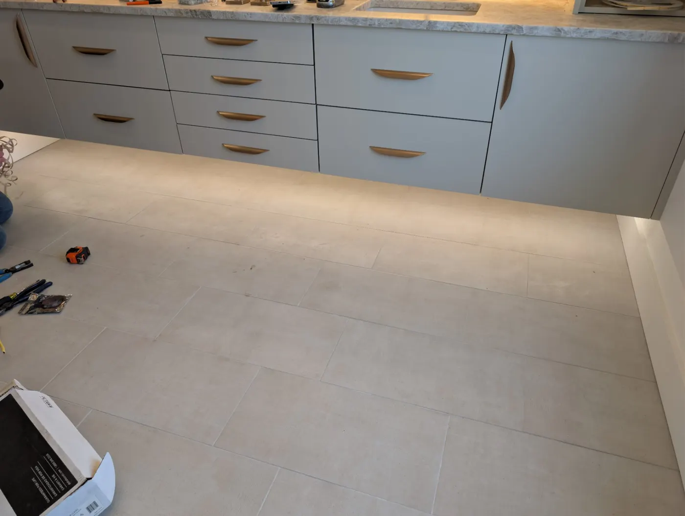 LED lighting under a long run of light gray cabinets washing across a new tile floor